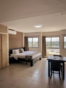 a bedroom with a bed and a table and window at Résidences Les Hauts de l'Indenié in Abidjan