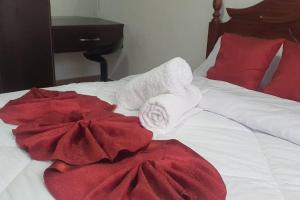 a bed with red and white towels on it at VillaRoma's Urban Retreat A Stylish Warm Loft in Eldoret