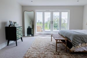 een slaapkamer met een bed, een spiegel en een dressoir bij 4BD Luxurious Countryside Retreat Scenic Views in Worplesdon