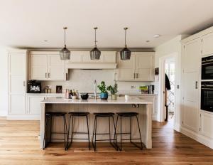 a kitchen with white cabinets and a island with bar stools at 4BD Luxurious Countryside Retreat Scenic Views in Worplesdon