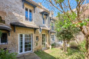 a large stone house with a patio in front of it at Augustine Beach - Maison à 700 m de la plage in Courseulles-sur-Mer