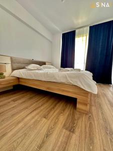 un grande letto in una camera da letto con pavimento in legno di SINAI APH Apartments a Sinaia