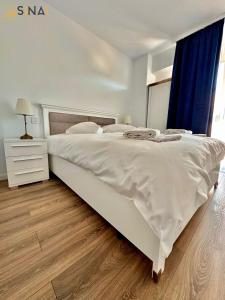 un grande letto bianco in una camera da letto con pavimento in legno di SINAI APH Apartments a Sinaia
