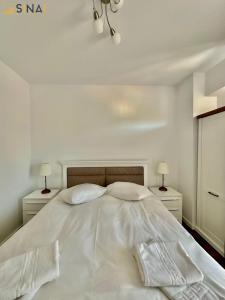 un letto bianco con lenzuola e cuscini bianchi di SINAI APH Apartments a Sinaia