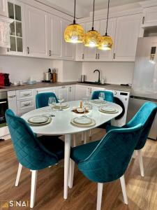 una cucina con tavolo bianco e sedie blu di SINAI APH Apartments a Sinaia