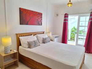 ein Schlafzimmer mit einem großen weißen Bett und einem Fenster in der Unterkunft Le Beau Manguier Residence in Pereybere