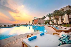 una piscina en un complejo con sillas y sombrillas en OSKENA Vacation Homes-Red Sea View Azzurra Salh Hasheesh Hurghada, en Hurghada
