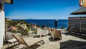 um homem de pé numa varanda com vista para o oceano em VILLA ROCCA BRUNA, LE CAP CORSE 5 ETOILES em Santa-Maria-di-Lota