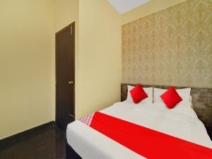 a bedroom with a bed with red pillows at OYO Flagship Mathrushree Lodge in Yelahanka