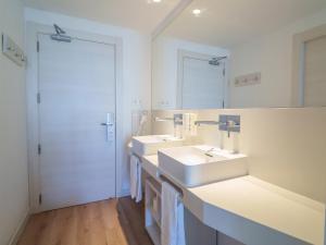a white bathroom with two sinks and a mirror at Spirit Hotel Benalmadena Beach in Benalmádena