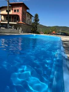 a swimming pool with blue water in front of a building at Къща за гости Пилигрим in Skrino