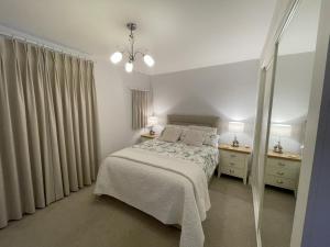 a white bedroom with a bed and two night stands at Pheasants Crossing - luxurious and cozy cottage in peaceful rural location in Almondbury