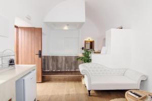 a living room with a white couch and a table at Santorini Rooftop Hot Tub Suite with Panoramic Views in Akrotiri
