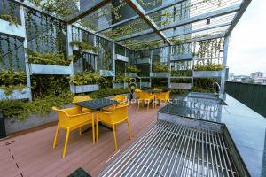 a conservatory with yellow chairs and tables and plants at Millerz Square Near MidValley by YourSuperhost in Kuala Lumpur