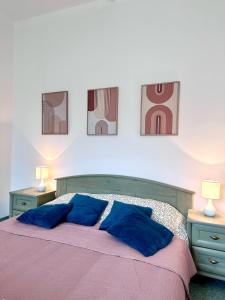 um quarto com uma cama com almofadas azuis e duas mesas em Éden Panzio em Bük