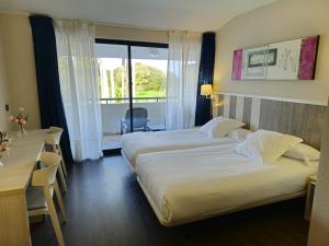 a hotel room with two beds and a desk and a window at Hotel La Palma de Llanes in Llanes