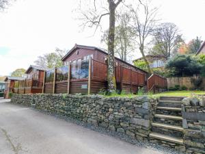 a house with a stone retaining wall and a stone fence at Shoreside Lodge in Bowness-on-Windermere