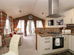 a kitchen with a stove top oven next to a living room at Shoreside Lodge in Bowness-on-Windermere