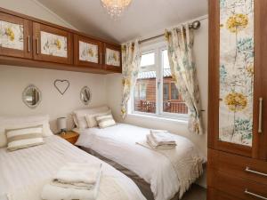 a bedroom with two beds and a window at Shoreside Lodge in Bowness-on-Windermere
