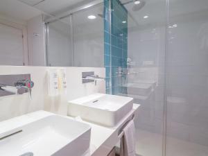 a white bathroom with two sinks and a glass shower at Spirit Hotel Benalmadena Beach in Benalmádena
