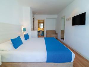 a bedroom with a large bed with blue pillows at Spirit Hotel Benalmadena Beach in Benalmádena