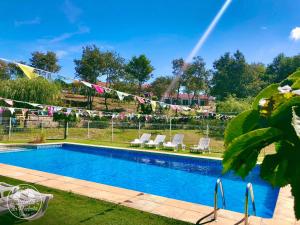 a swimming pool with two lawn chairs and a rainbow at Casa 2 do Pavilhão da Prelada in Celorico de Basto