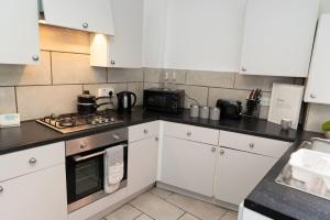 uma cozinha com armários brancos e um forno com placa de fogão em Shelen View em Saint Helens