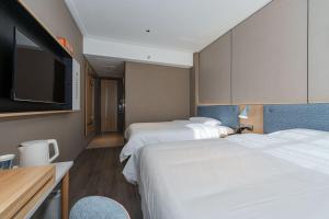 a hotel room with two beds and a flat screen tv at Home Inn Zhangjiajie Tianmen Mountain Branch in Zhangjiajie