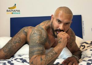 um homem com tatuagens nos braços deitado numa cama em Banana Gay House - Only Men em Sevilha