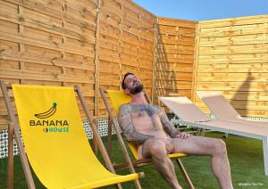 um homem com uma tatuagem sentado numa cadeira amarela em Banana Gay House - Only Men em Sevilha