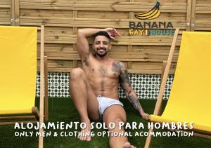 um homem sem camisa sentado na relva em frente a uma parede em Banana Gay House - Only Men em Sevilha