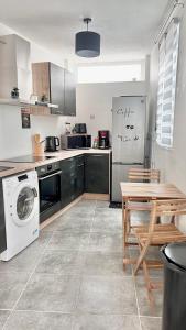 une cuisine avec une machine à laver, une table et un réfrigérateur dans l'établissement Le Duplex, 1 chambre, Parking gratuit & Wifi, à Ruelle-sur-Touvre