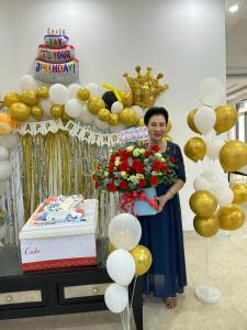 a woman standing in front of a cake and balloons at Minh Phước Villa 12 Kim Ngân in Vung Tau
