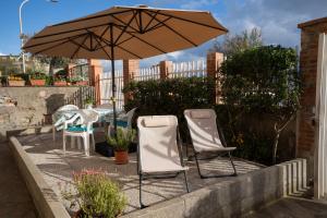 - une terrasse avec 2 chaises et un parasol dans l'établissement Da Nonna Tina VistaMare, à Piombino