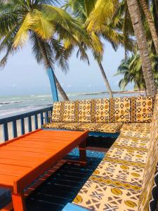 an orange bench sitting on a balcony with palm trees at Rent your own private beach bungalow in Ampeni