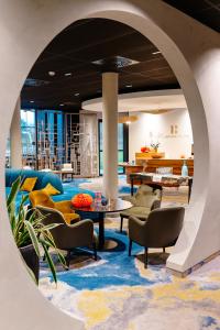 een lobby met stoelen, tafels en eettafels bij Best Western Plus Hotel & Restaurant Les Humanistes Colmar Nord in Sélestat
