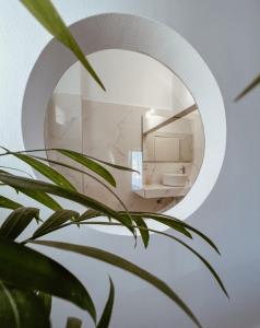 a bathroom with a round mirror and a plant at Danae Villa in Fira