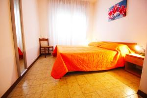 1 dormitorio con 1 cama con colcha de color naranja en Residence Tonin Trilocale, en Bibione