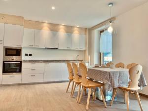 a kitchen with white cabinets and a table and chairs at Cesa Do Ruf eurochalet in Campitello di Fassa