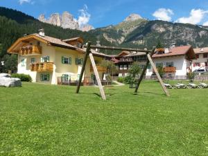 a swing set in a field in front of a building at Residence Ercabuan in Campitello di Fassa +4 photos