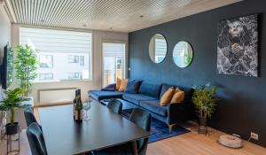 a living room with a blue couch and a table at Arctic Homes - Premium Aurora Apartment in Tromsø