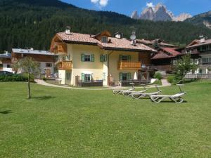 a building with a bunch of chairs in the grass at Residence Ercabuan in Campitello di Fassa
