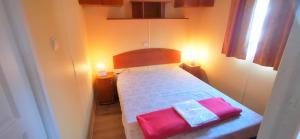 een kleine slaapkamer met een bed met 2 roze kussens bij locationestivale40 Bungalow petit budget océan forêt in Bias