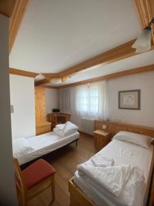 ein Zimmer mit 2 Betten und einem Stuhl darin in der Unterkunft Hotel Aplis in Ovaro