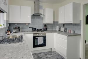 uma cozinha com armários brancos e um forno em Stunning and Lovely 3 Bed House - Catch 22 em Coventry