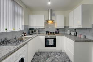 uma cozinha com armários brancos e um forno com placa de fogão em Stunning and Lovely 3 Bed House - Catch 22 em Coventry