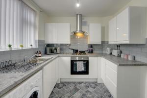 a kitchen with white cabinets and a stove top oven at Stunning and Lovely 3 Bed House - Catch 22 in Coventry