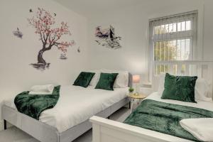 a bedroom with two beds and a tree on the wall at Stunning and Lovely 3 Bed House - Catch 22 in Coventry
