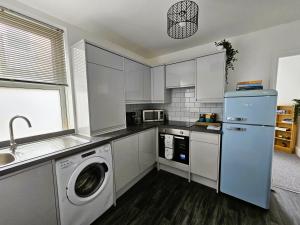 cocina con armarios blancos, lavadora y secadora en Spacious 2 Bed Flat in Central Plymouth, en Plymouth