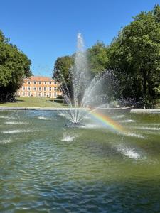 a fountain with a rainbow in the middle of a pond at Château de Roquelune in Pézenas